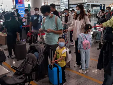 Orang-orang mengantre check-in untuk penerbangan domestik menjelang liburan "Golden Week" di Bandara Internasional Ibu Kota Beijing pada 30 September 2020. Gelombang liburan melanda China yang warganya merayakan libur panjang, yang dikenal dengan Golden Week. (NICOLAS ASFOURI / AFP)
