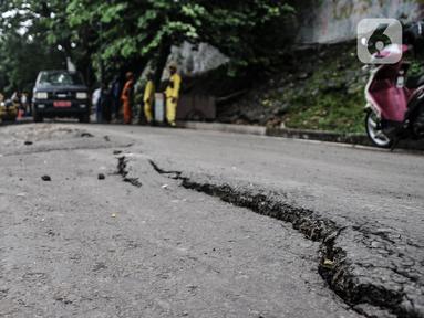 Petugas Sudin Bina Marga Jakarta Pusat memperbaiki jalan ambles di Jalan Inspeksi Kali Ciliwung, Kenari, Rabu (19/1/2022). Jalan yang berada di belakang RSCM tersebut ambles sepanjang 40 meter akibat terkikis oleh hujan deras kemarin sehingga menyulitkan akses warga. (merdeka.com/Iqbal S Nugroho)