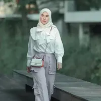 Irish Bella cukup rutin membagikan inspirasi mix and match kemeja putih. Seperti di foto ini, ia memilih kemeja putih dengan detail pita sampai renda yang dipasangkan dengan celana cargo yang romantis dengan aksen ruffle (Foto: Instagram_irishbella_)