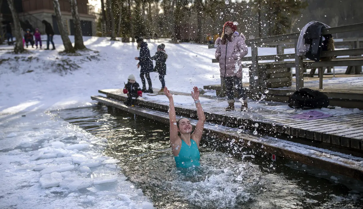 Seorang wanita mandi di lubang es di danau dekat Vilnius, Lithuania, Minggu (13/2/2022). Suhu udara 0 derajat Celcius (32 derajat Fahrenheit). (AP Photo/Mindaugas Kulbis)