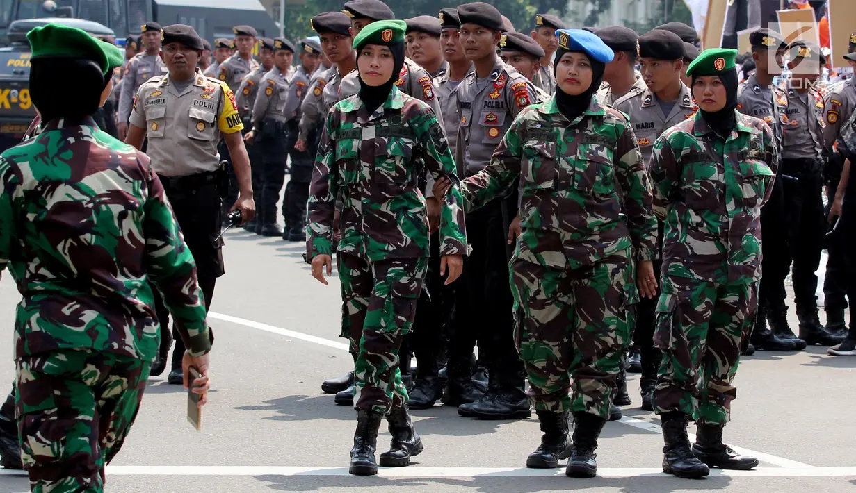 Aparat TNI wanita berjaga saat Hari Buruh Sedunia di depan Istana Negara, Jakarta, Selasa (1/5). Para buruh berbondong-bondong datang menuju Istana Kepresidenan membawa bendera dan atribut masing-masing serikat kerjanya. (Liputan6.com/Johan Tallo)