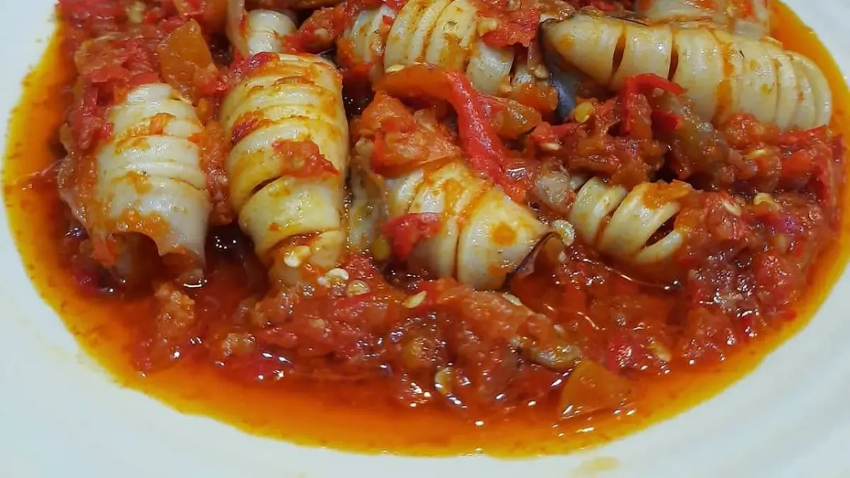 Foto cumi sambal balado disajikan di atas piring putih dengan warna merah cerah dari sambal yang menggugah selera
