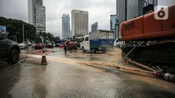 Petugas membersihkan jalan dari genangan air akibat kebocoran saluran pipa air di kawasan Bundaran Hotel Indonesia (HI), Jakarta, Selasa (11/10/2022). Kebocoran pipa air diduga terimbas proyek revitalisasi Halte Bundaran Hotel Indonesia. (Liputan6.com/Faizal Fanani)