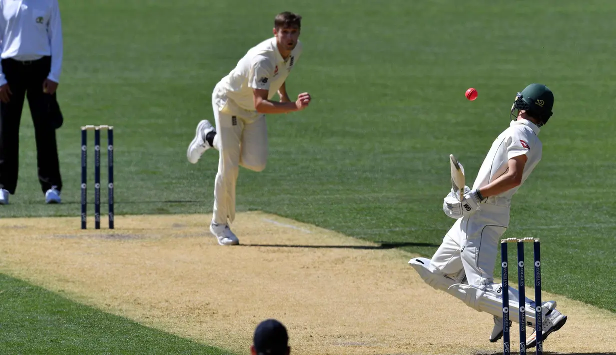 Pemain kriket Australia XI, Jake Carder (kanan) menghindari bola yang dilempar pemain Inggris, Chris Woakes (tengah) saat bertanding pada hari kedua pertandingan empat hari Ashes di Adelaide Oval di Adelaide (9/11). (AFP Photo/Saeed Khan)