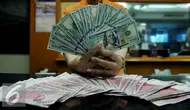 Petugas memperlihatkan uang pecahan US$100 dan rupiah di pusat penukaran uang, Jakarta, , Rabu (12/8/2015). Reshuffle kabinet pemerintahan Jokowi-JK, nilai Rupiah terahadap Dollar AS hingga siang ini menembus Rp 13.849. (Liputan6.com/Johan Tallo)