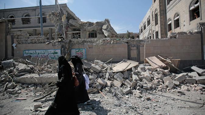 Dua orang wanita berjalan melewati puing-puing gedung yang runtuh di kompleks kepresidenan, di Sanaa, Yaman (7/5). Jet tempur koalisi yang dipimpin Arab Saudi melancarkan serangan udara ke istana kepresidenan Yaman. (AP Photo/Hani Mohammed)