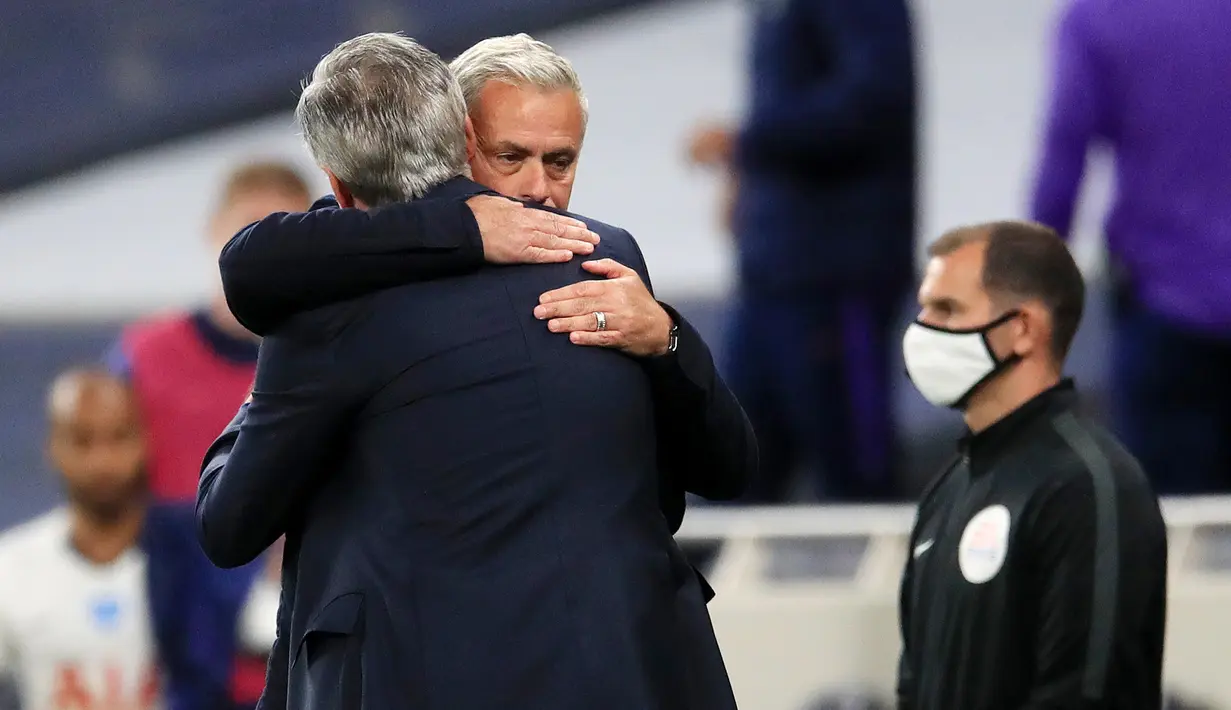 Pelatih Tottenham Hotspur, Jose Mourinho, berpelukan dengan pelatih Everton, Carlo Ancelotti, pada laga Premier League, Senin (6/7/2020). Mourinho melanggar aturan jarak sosial demi memeluk Carlo Ancelotti yang merupakan idolanya. (AFP/Adam Davy)