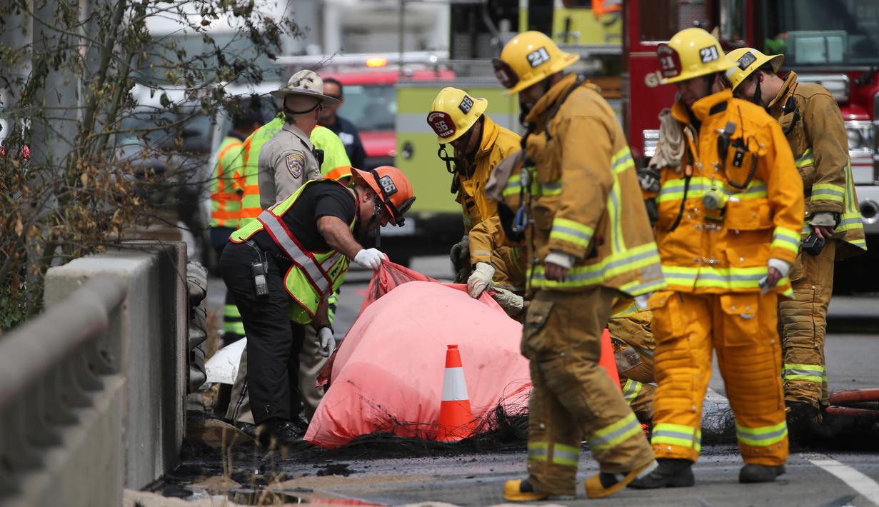 Penyidik melihat mayat korban akibat tabrakan antara dua truk besar di utara pusat kota Los Angeles (25/4). Kecelakaan ini menewaskan satu orang dan melukai sejumlah orang lainnya. (AP Photo/Reed Saxon)