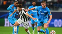 Pada menit ke-26 gantian Juventus yang memperoleh peluang. Penetrasi Federico Chiesa (tengah) berhasil melewati dua pemain belakang Zenit, untuk kemudian melepaskan tembakan yang masih mampu diblok lawan. (AFP/Olga Maltseva)