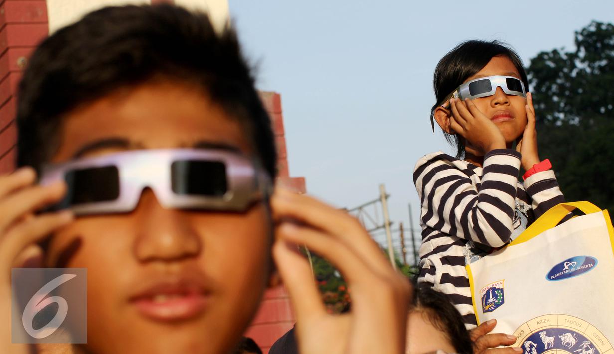 Seorang anak mengunakan kacamata menyaksikan proses Gerhana Matahari Total (GMT) 2016 di halaman Taman Ismail Marzuki (TIM), Jakarta, Rabu (9/3). Di Jakarta, gerhana matahari terjadi sebesar 88,76 persen selama sekitar 2. (Liputan6.com/Fery Pradolo)