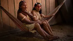 Dua perempuan adat Waorani beristirahat di tempat tidur gantung di desa Nemompare, di tepi sungai Curaray, di provinsi Pastaza, Ekuador (14/4/2019). Suku Waorani dari Amazon Ekuador berdemo di depan pengadilan memprotes perusahaan minyak keluar dari wilayah mereka. (AFP Photo/Rodrigo Beundia)