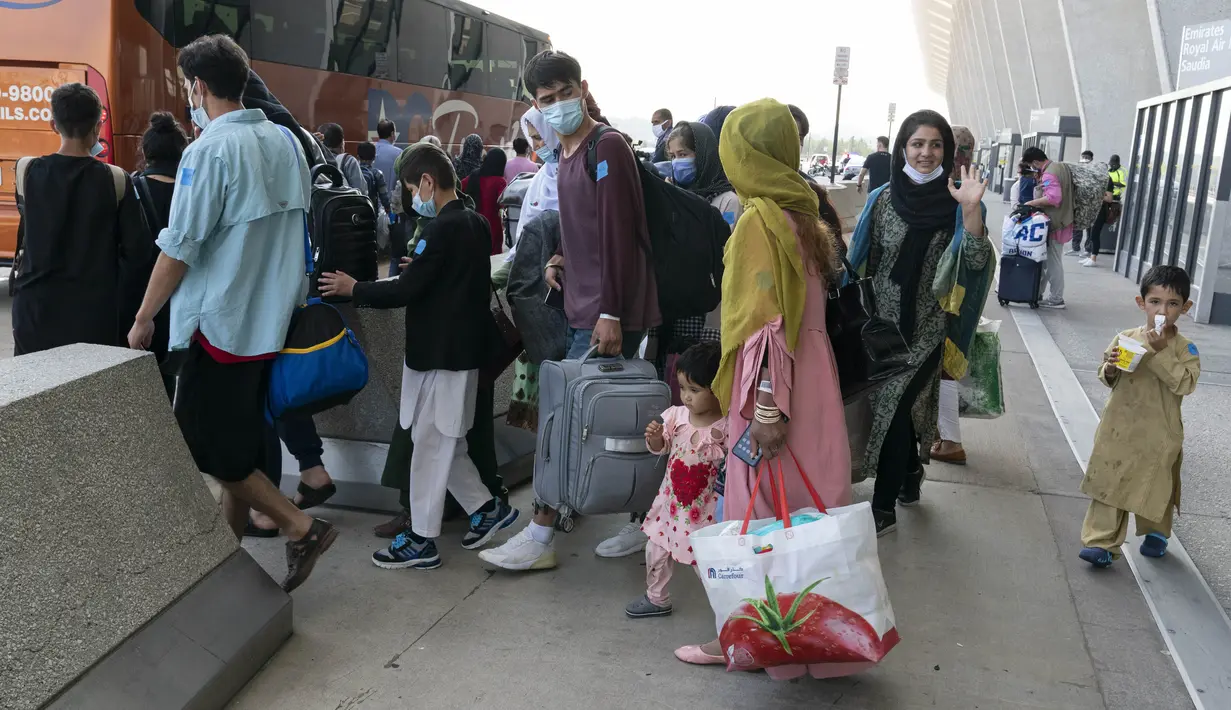 Keluarga dievakuasi dari Kabul, Afghanistan, menunggu untuk naik bus setelah mereka tiba di Bandara Internasional Washington Dulles, di Chantilly, Va, Rabu (25/8/2021). (AP Photo/Jose Luis Magana)