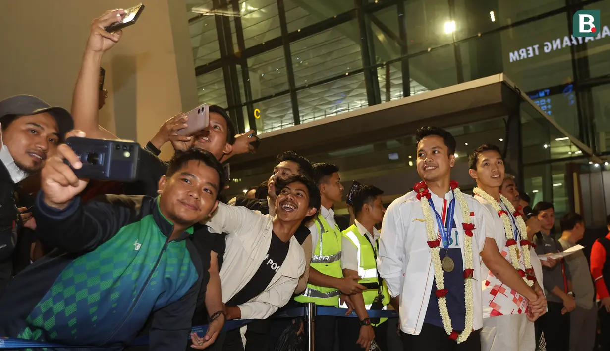 <p>Para fans melakukan swafoto dengan dua tunggal putra Indonesia, Anthony Ginting dan Jonatan Christie saat acara penyambutan para juara All England 2024 di Terminal 3 Bandara Soekarno Hatta, Tangerang, Banten, Senin (18/3/2024) malam WIB. (Bola.com/M Iqbal Ichsan)</p>