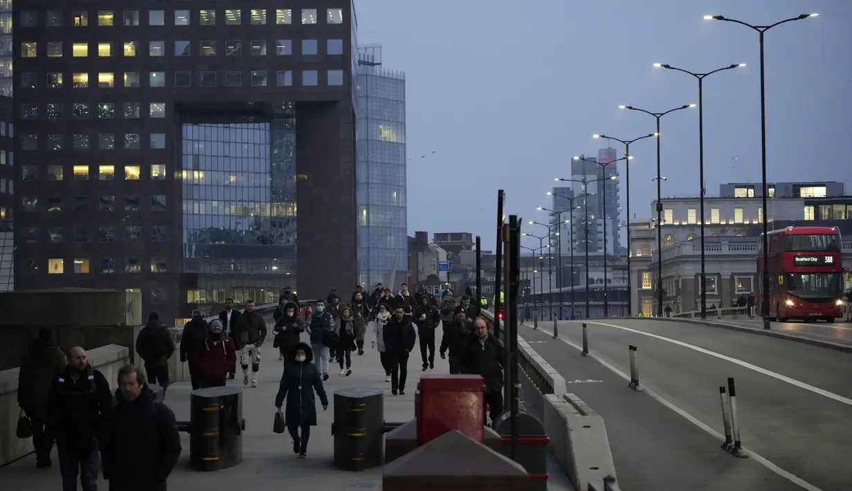 Pekerja berjalan di atas Jembatan London menuju distrik keuangan Kota London selama jam sibuk pagi hari, di London, Senin (24/1/2022). Pemerintah Inggris telah meminta orang-orang untuk kembali bekerja di kantor mulai Senin karena mereka melonggarkan pembatasan corona COVID-19. (AP Photo/Matt Dunham