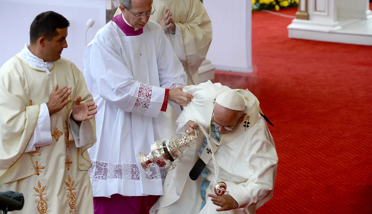 Paus Fransiskus dibantu berdiri usai terjatuh saat berjalan menuju altar terbuka untuk merayakan misa di biara Jasna Gora, Polandia, Kamis (28/7). Kunjungan Paus Fransiskus ke Polandia untuk menghadiri perayaan World Youth Day. (FILIPPO MONTEFORTE/AFP)