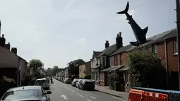Patung dengan nama Headington Shark tampak menerobos atap rumah di wilayah pinggiran Oxford, Inggris pada 30 April 2019. Bagian kepalanya tidak terlihat karena dibuat seakan masuk ke dalam atap, sedangkan badan hingga ekornya menjulang ke langit dengan posisi terbalik.  (AP Photo/Matt Dunham)