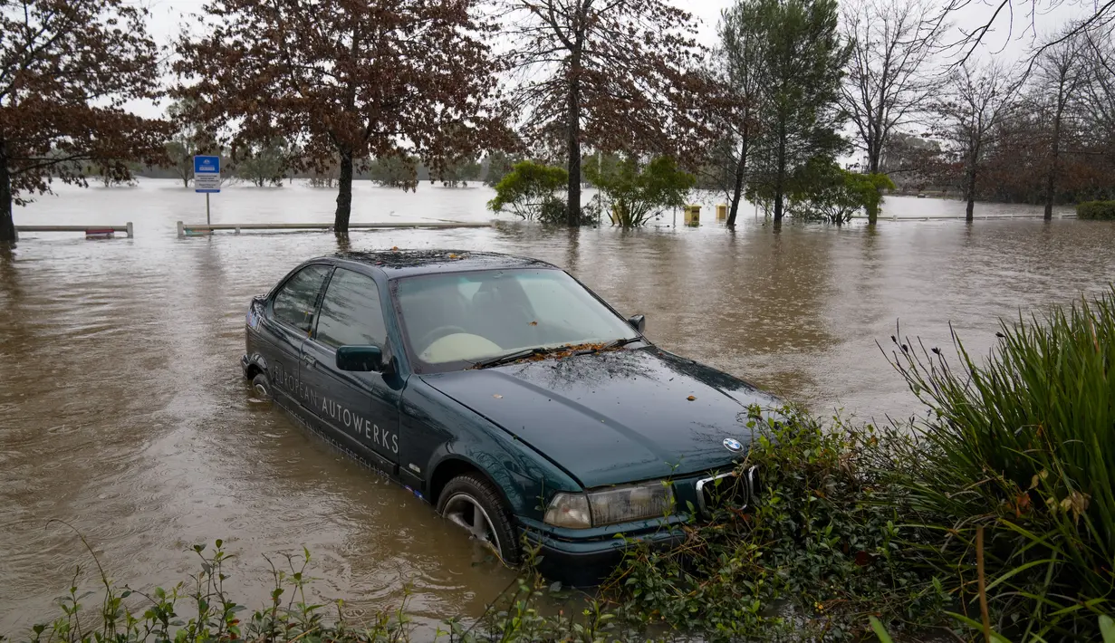 Sebuah mobil terendam dalam air banjir di Camden di pinggiran Sydney, Australia, Senin (4/7/2022). Lebih dari 30.000 penduduk Sydney dan sekitarnya telah diberitahu untuk mengungsi atau bersiap untuk meninggalkan rumah mereka pada hari Senin di tengah kondisi cuaca yang buruk. (AP Photo/Mark Baker)