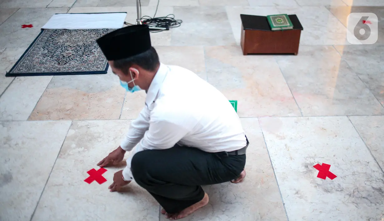 Petugas memasang tanda silang antar saf di Masjid Istiqlal, Jakarta Pusat, Selasa (2/6/2020). Masjid Istiqlal merupakan salah satu sarana ibadah yang dipersiapkan menerapkan prosedur standar new normal atau kenormalan baru. (Liputan6.com/Faizal Fanani)
