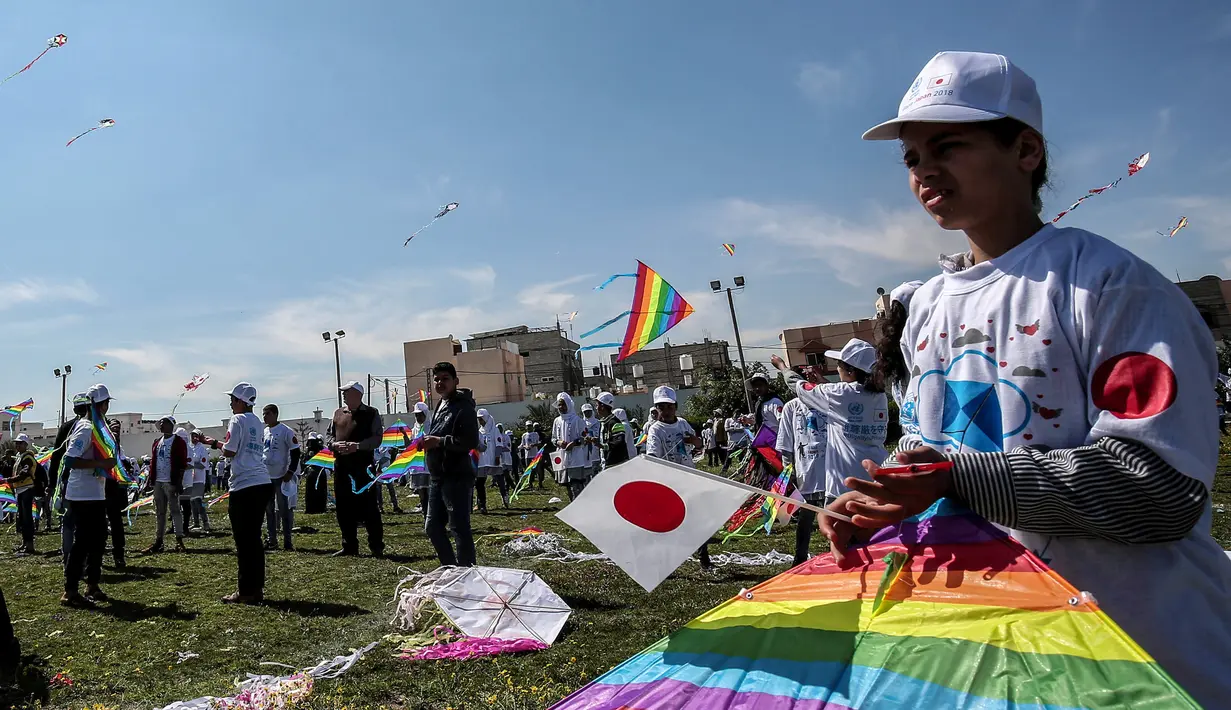 Seorang anak Palestina membawa layangan warna-warni dan bendera Jepang dalam aksi solidaritas peringatan tujuh tahun gempa dan tsunami Jepang di Gaza, Selasa (13/3). (SAID KHATIB/AFP)