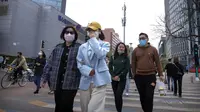 Orang-orang yang memakai masker berjalan melintasi persimpangan di Beijing, China, 13 April 2022. Shanghai bergerak untuk lebih melonggarkan lockdown di kota terbesar di China tersebut yang tampaknya terhenti. (AP Photo/Mark Schiefelbein)