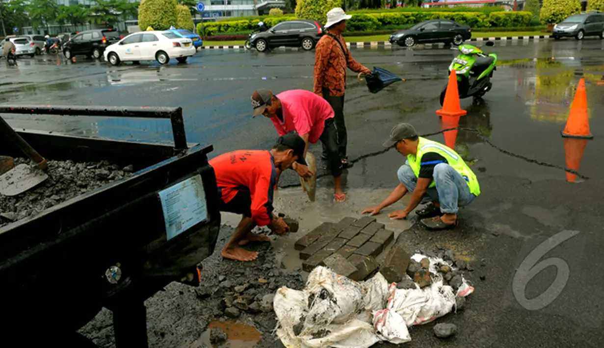 Sejumlah pekerja memperbaiki jalan yang rusak akibat banjir di kawasan Kelapa Gading. Sebelumnya, kawasan ini terendam banjir setinggi 80 cm hingga memutuskan arus lalu lintas, Jakarta, Jumat (13/2/2015). (Liputan6.com/Faisal R Syam)