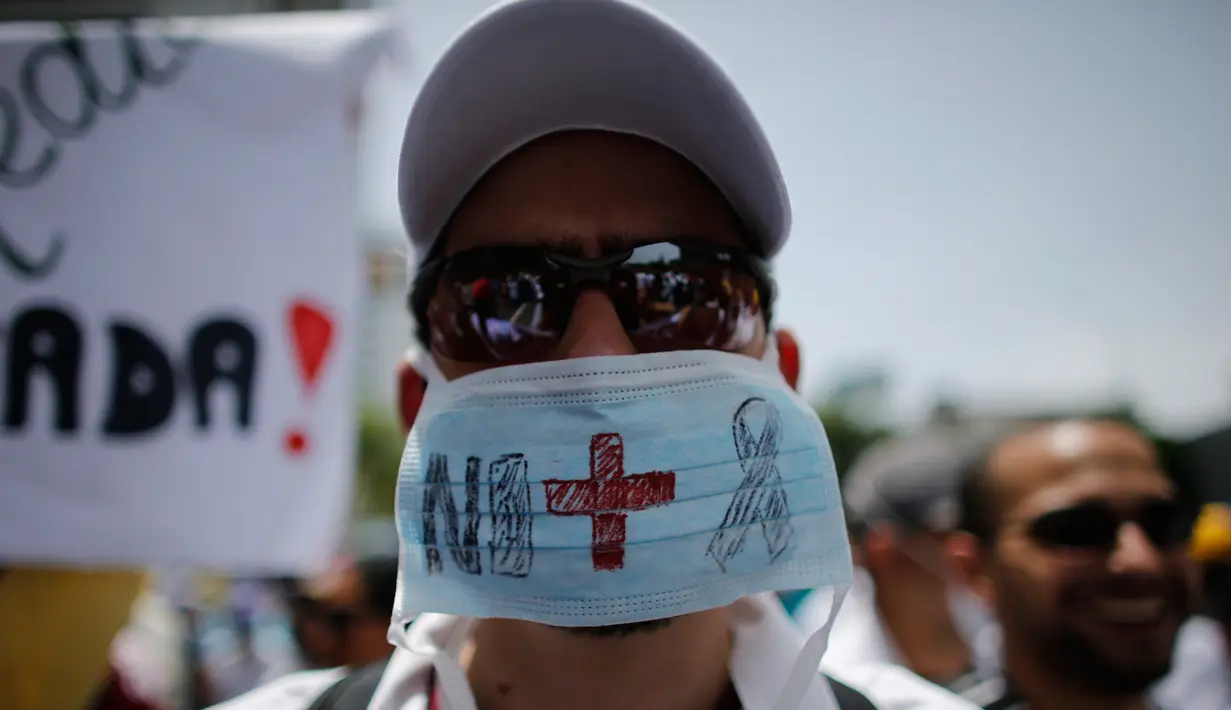 Seorang dokter memakai masker saat unjuk rasa menuntut Presiden Venezuela Nicolas Maduro karena memburuknya ekonomi dan kondisi kemanusiaan di Caracas, Venezuela, (22/5). Sedikitnya 46 orang telah meninggal dunia. (AP Photo/Ariana Cubillos)