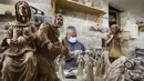 Seorang tukang kayu Palestina mengukir patung keagamaan dari kayu zaitun di sebuah toko dekat Church of the Nativity, Betlehem, Tepi Barat, 21 Desember 2020. Bahan dasar pembuatan patung tersebut menggunakan kayu zaitun. (HAZEM BADER/AFP)