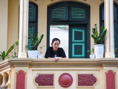 Gambar pada 3 September 2021 menunjukkan seorang perempuan melihat keluar dari balkon rumahnya di Hanoi, Vietnam, selama lockdown Covid-19. Menghadap ke jalan yang sepi, balkon kecil mereka menjadi saksi bisu terkait aktivitas yang dilakukan oleh masing-masing keluarga. (Nhac NGUYEN/AFP)
