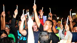 Pasca-eksekusi mati, empat rekan duo Bali Nine, Andrew Chan dan Myuran Sukumaran terlihat menyalakan lilin saat menggelar doa bersama di depan pagar Dermaga Wijaya Pura, Cilacap, Jateng, Rabu (29/4/2015) dini hari. (Liputan6.com/Yoppy Renato)