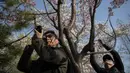 Pengunjung mengabadikan gambar bunga sakura yang bermekaran di Taman Yuyuantan, Beijing, 24 Maret 2019. Di taman tersebut ditanam sebanyak 2.000 pohon sakura dari 18 jenis yang bermekaran setiap musim semi pada akhir bulan Maret sampai April. (Nicolas ASFOURI / AFP)
