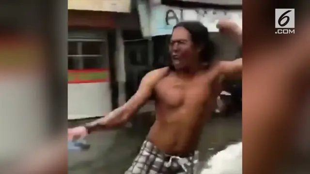 Seorang pria mencoba mencari hiburan di tengah banjir. Ia berselancar dengan ditarik sepeda motor.