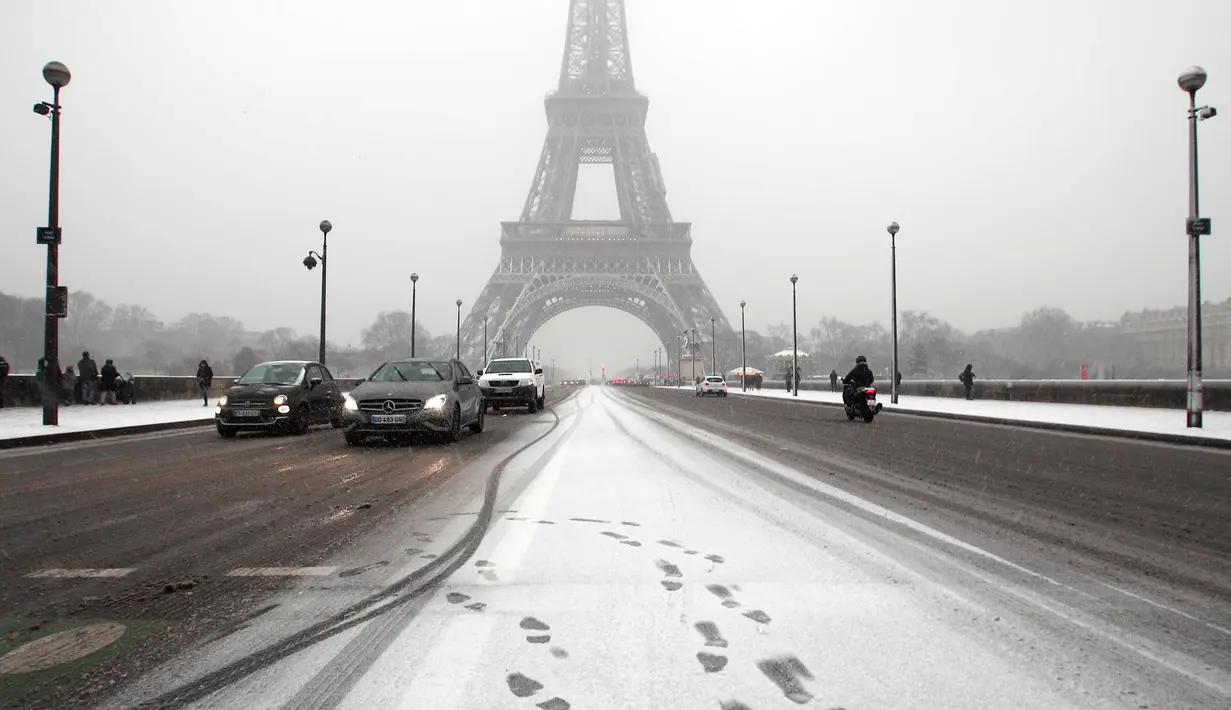 Suasana di Menara Eiffel saat turun salju di Paris, Prancis, (6/2). Sebelumnya Paris mengalami banjir bandang  akibat meluap Sungai Seine yang dipicu oleh curah hujan tinggi. (AP Photo / Francois Mori)