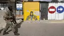 Seorang anggota Pasukan Pertahanan Afrika Selatan (SANDF) berjalan melewati mural yang mengiklankan penjualan masker saat berpatroli di di Alexandra, Johannesburg, Kamis (15/7/2021). Patroli tersebut menyusul kerusuhan massa yang disebabkan dipenjaranya mantan Presiden Jacob Zuma (Phill Magakoe/AFP)
