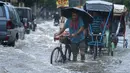 Seorang pria membawa tabung gas di sepedanya dan menyeberangi jalan yang banjir saat hujan deras di Guwahati, negara bagian Assam, India, Kamis (16/6/2022). Pemerintah Assam telah memerintahkan penutupan semua institusi pendidikan di Guwahati karena peringatan siaga merah untuk hujan lebat. (AP Photo/Anupam Nath)