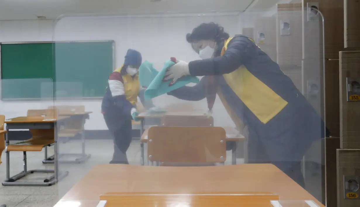 Petugas mendisinfeksi pembatas plastik pada meja untuk ujian masuk perguruan tinggi, Seoul, Korea Selatan, Selasa (1/12/2020). Sekitar 490.000 siswa lulusan sekolah menengah atas di Korea Selatan akan menjalani Tes Kemampuan Skolastik Perguruan Tinggi pada 3 Desember 2020. (AP Photo/Ahn Young-joon)