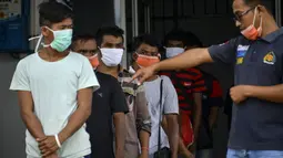 Seorang pejabat Urusan Kelautan dan Perikanan Indonesia (R) berdiri di sebelah nelayan Myanmar yang menunggu untuk dideportasi setelah ditahan selama delapan bulan di Banda Aceh (5/8/2020). (AFP Photo/Chaideer Mahyuddin)