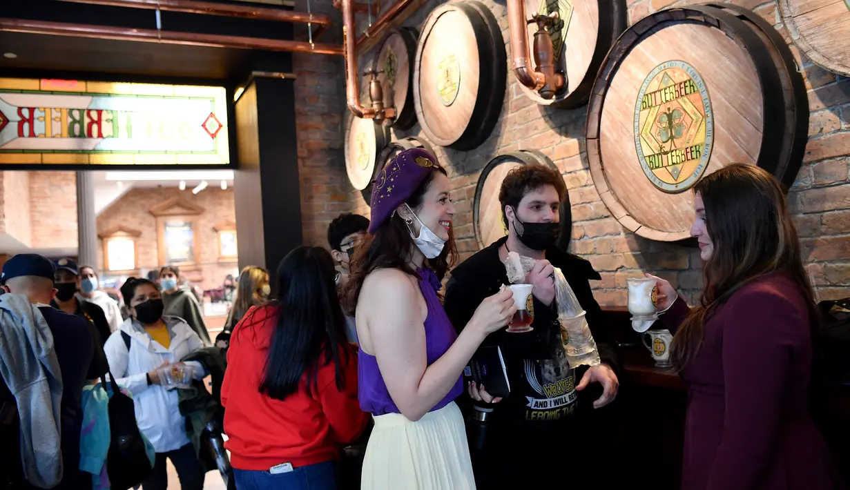 Orang-orang minum 'Butterbeer' di dalam toko Harry Potter Terbesar di Dunia saat resmi dibuka di New York City, Kamis (3/6/2021). Pengunjung bisa menjelajahi 15 area dengan tema berbeda, produk eksklusif, serta elemen interaktif yang mengingatkan pada dunia sihir Harry Potter. (Angela Weiss / AFP)