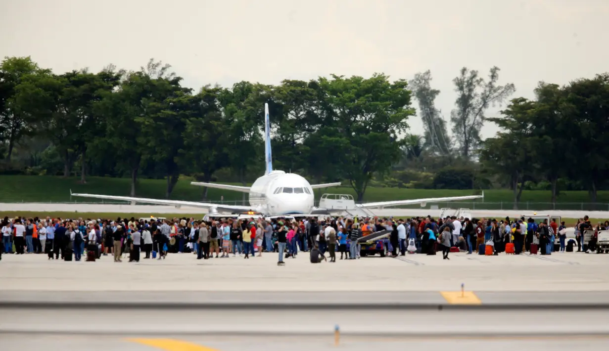 Penumpang dievakuasi di landasan pesawat saat penembakan di Bandara Fort Lauderdale, Florida, AS (6/1). Menurut polisi, pelaku penembakan tiba dari penerbangan Kanada dan tengah melakukan pemeriksaan bagasi kedatangan. (Al Diaz /Miami Herald via AP)
