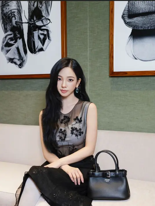 Karina Aespa tampil dengan super atraktif dengan sheer sleevless top dengan detial black floral dan Prada buckle small leather bag dengan aksentuasi belt. / Foto dok: Prada.