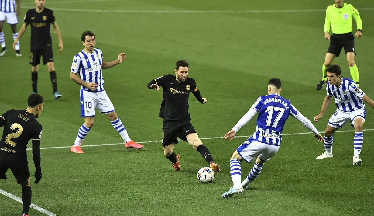Penyerang Barcelona, Lionel Messi berusaha melewati pemain Real Sociedad, Martin Merquelanz pada pertandingan La Liga Spanyol di stadion Reale Arena, Spanyol (22/3/2021).Barcelona tertinggal empat poin dari Atletico Madrid (66) yang menempati posisi puncak klasemen. (AP Photo/Alvaro Barrientos)