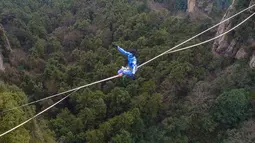 Kontestan berpakaian karakter Avatar bergaya saat melintasi slackline di Pegunungan Huangshizhai di Zhangjiajie, Hunan, China, Minggu (23/12). Pemandangan tersebut memberi sensasi bukit-bukit yang melayang, persis di film Avatar. (STR/AFP)