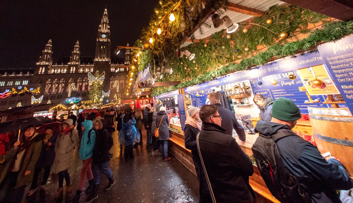 Wisawatan mengunjungi stand yang ada di pasar Natal di luar City Hall, Wina pada 26 November 2018. Di Pasar Natal ini, para pengunjung bisa menikmati jajanan khas hingga pernak-pernik kerajinan tangan asli Austria. (JOE KLAMAR / AFP)