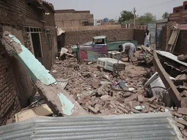 Seorang pria membersihkan puing-puing rumah yang terkena serangan dalam pertempuran baru-baru ini di Khartoum, Sudan, Selasa, 25 April 2023. (AP Photo/Marwan Ali)