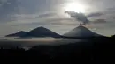 Gunung Agung mengembuskan asap saat matahari terbit (sunrise) terlihat dari Kintamani, Bali, Rabu (13/12). Visual Gunung Agung tampak cerah, asap yang keluar dari kawah gunung itu masih rutin keluar meski tidak secara menerus. (AP Photo/Firdia Lisnawati)
