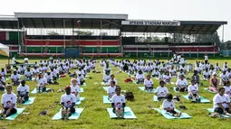 Ratusan warga melakukan gerakan yoga saat mengikuti yoga massal di Stadion Afraha, Nakuru, Kenya (15/6/2019). Hari Yoga Internasional, yang setiap tahun dirayakan pada 21 Juni, pertama kali diusulkan Perdana Menteri India Narendra Modi pada 2014 ke Majelis Umum PBB. (AFP Photo/Suleiman Mbatiah)