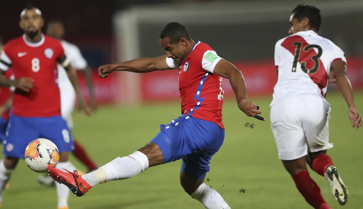 Bek Chile, Jean Beausejour (tengah) menendang bola di samping gelandang Peru, Renato Tapia dari Peru dalam laga Kualifikasi Piala Dunia 2022 zona Conmebol di Estadio Nacional, Santiago, Jumat (13/11/2020). Chile mengalahkan Peru 2-0 berkat gol yang diborong Arturo Vidal. (IVAN ALVARADO / POOL / AFP)