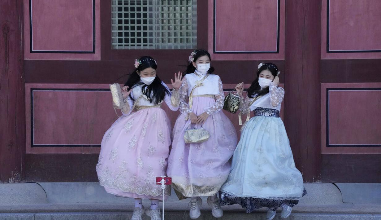 Siswa sekolah menengah yang mengenakan masker sebagai tindakan pencegahan terhadap virus corona melompat untuk selfie saat merayakan liburan Chuseok, Hari Thanksgiving versi Korea, di Istana Gyeongbok di Seoul, Korea Selatan, Rabu (22/9/2021). ( AP Photo/Ahn Young-joon)