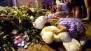 Seorang anak meletakkan boneka beruang didekat karangan bunga di depan Kedutaan Besar Belanda di Kiev, Ukraina, Jumat (17/7/14). (AFP PHOTO/Sergei Supinsky)