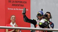 Pembalap LCR Honda, Cal Crutchlow merayakan kemenangannya pada balapan MotoGP Argentina di atas podium Sirkuit Termas de Rio Hondo, Minggu (8/4). Kemenangan ini menempatkan Crutchlow di puncak klasemen sementara dengan poin 38. (AP/Natacha Pisarenko)
