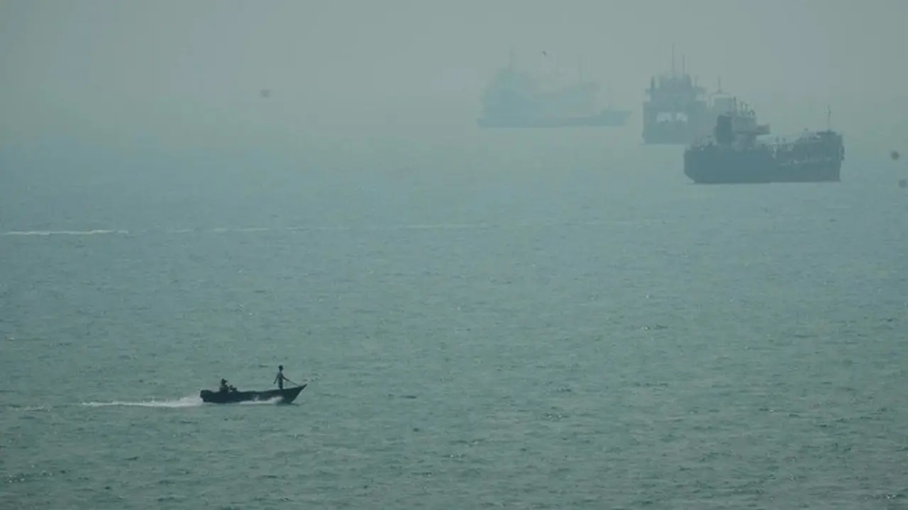 Sebuah perahu motor melintas di dekat kapal-kapal komersial yang berlabuh di tengah kabut di Selat Hormuz, lepas pantai Bandar Abbas, Iran, Senin (7/9/2026).